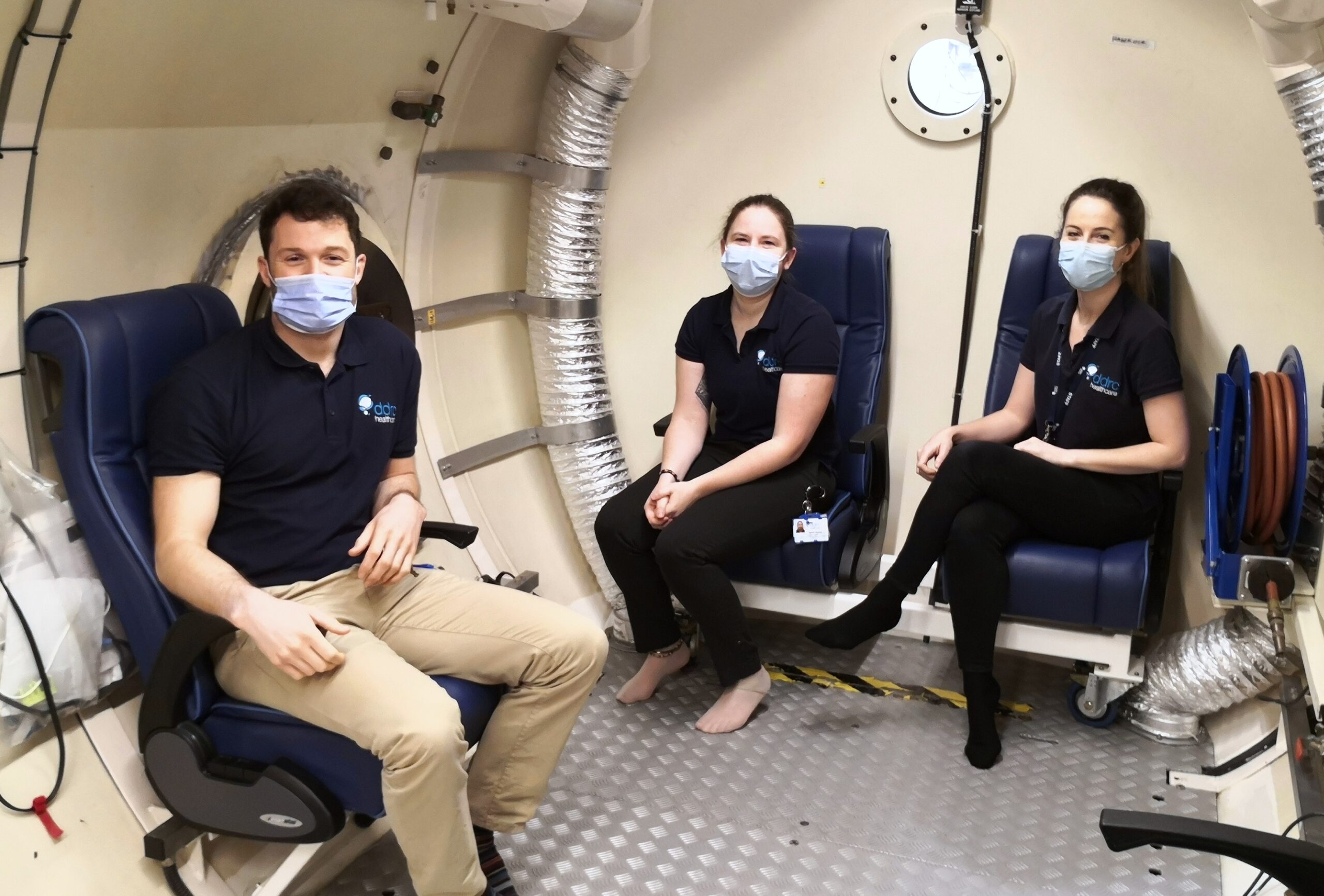 Three doctors sat inside a hyperbaric chamber