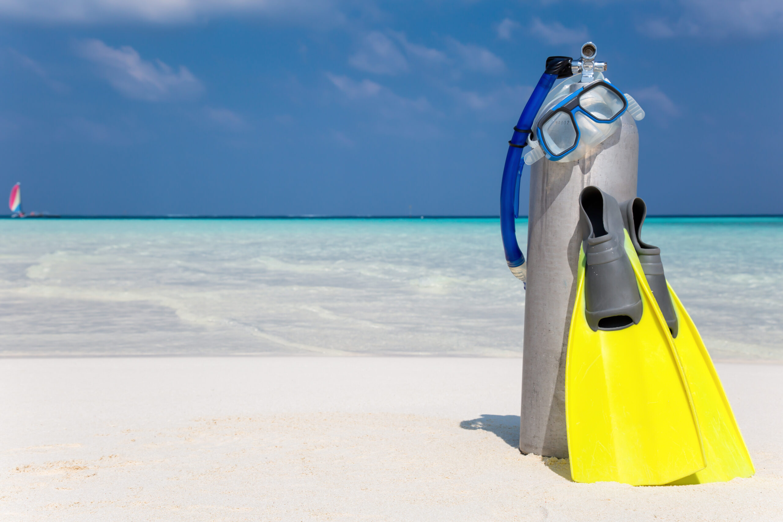 Scuba tank and flippers on beach