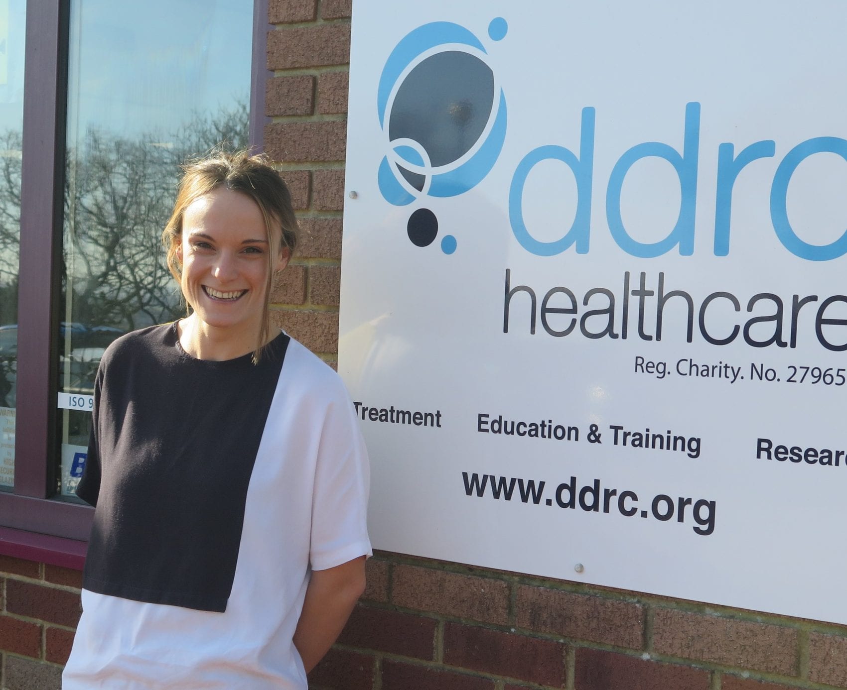 Dr Lizzie Freeman standing beside DDRC signage